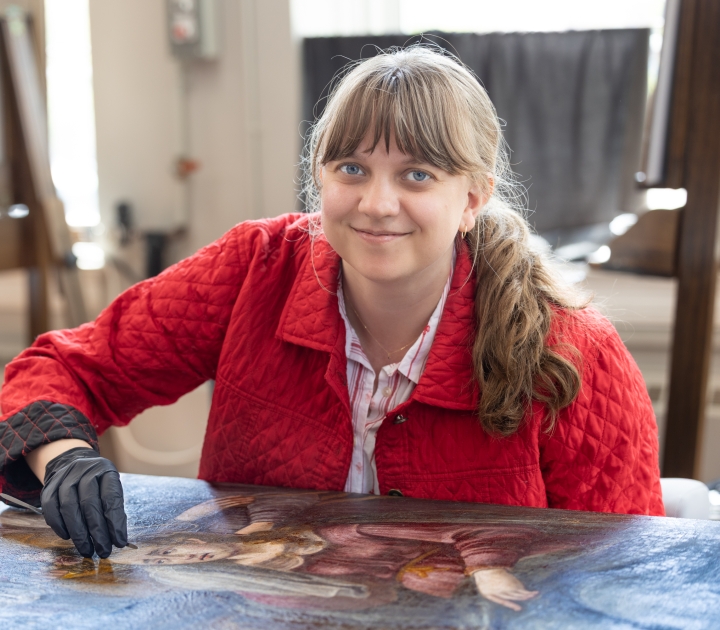 A female student working on conserving a painting